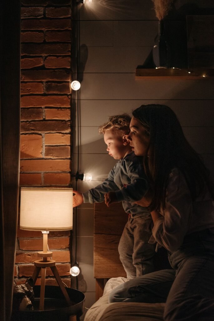 Vibrant Mornings & Radiance A mother and child share a tender moment under warm lamp light beside a brick wall.